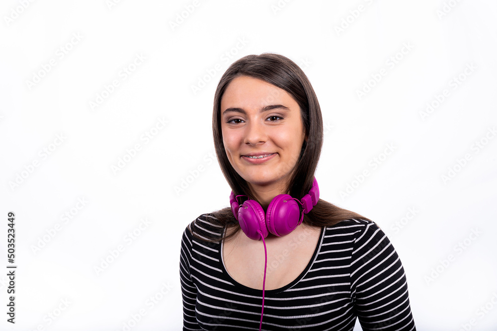 Portrait of beautiful smiling girl with long hair. The young woman wears jeans and a striped shirt and uses headphones to listen to music. Portrait of beautiful smiling girl with long hair. The young woman wears jeans and a striped shirt and uses headphones to listen to music.