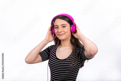 Portrait of beautiful smiling girl with long hair. The young woman wears jeans and a striped shirt and uses headphones to listen to music.