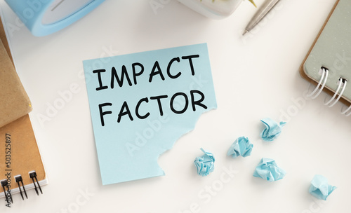 IMPACT FACTOR. text on white paper in a red notepad near different stationery
