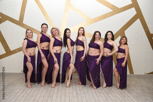 A group of beautiful girls in the outfits of oriental dancers in the studio stand in a row posing as in an oriental harem photo