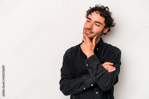 Young caucasian man isolated on white background relaxed thinking about something looking at a copy space.