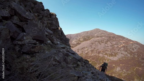 A man climbing up a big mountain in the Rhinog mountains wales UK photo