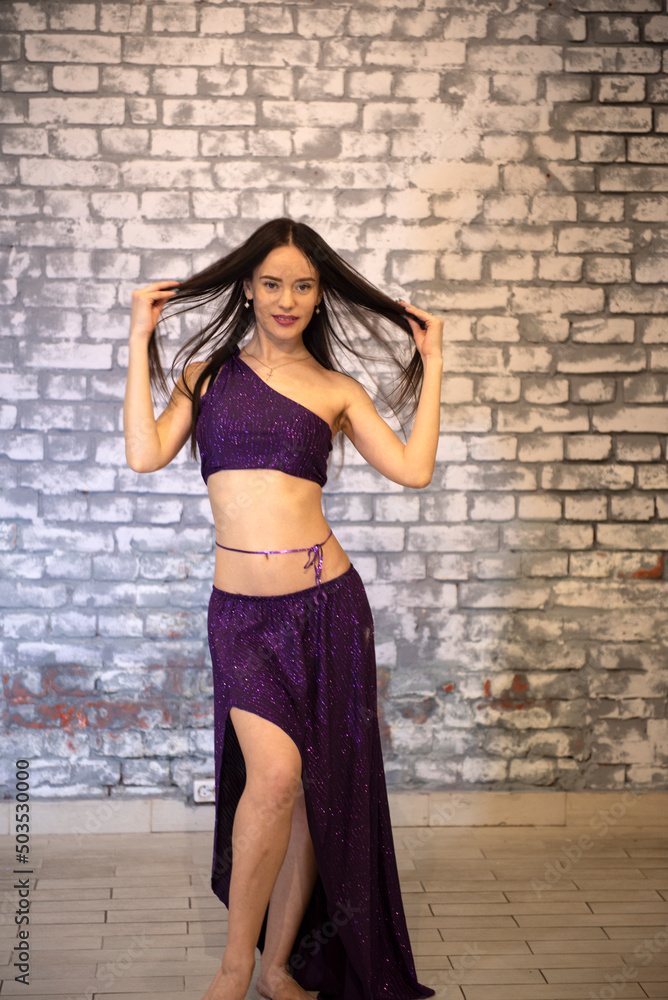 A beautiful model dancer in the studio against a brick wall in an oriental outfit in a model pose A beautiful model dancer in the studio against a brick wall in an oriental outfit in a model pose