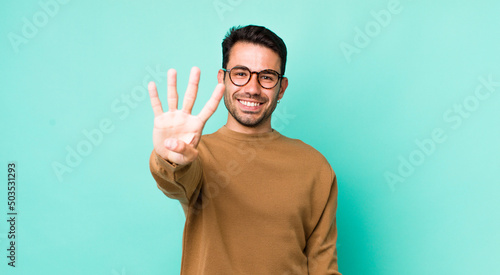 young handsome hicpanic man smiling and looking friendly, showing number four or fourth with hand forward, counting down photo