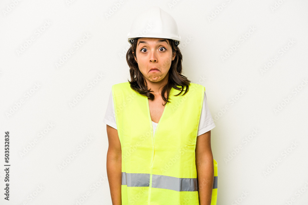 Young laborer hispanic woman isolated on white background shrugs shoulders and open eyes confused. Young laborer hispanic woman isolated on white background shrugs shoulders and open eyes confused.