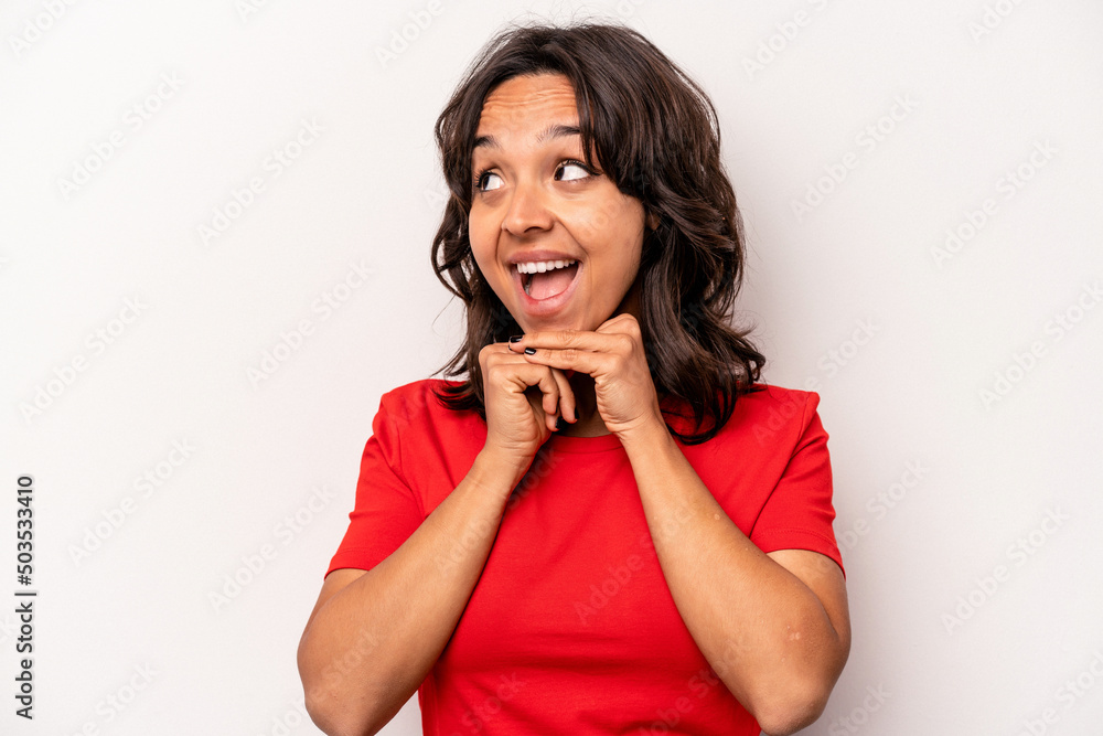 Young hispanic woman isolated on white background keeps hands under chin, is looking happily aside. Young hispanic woman isolated on white background keeps hands under chin, is looking happily aside.