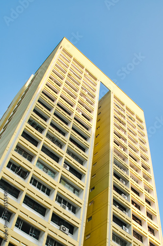 Abstract picture of a tall yellow apartment building creating a strong contrast to the clear blue sky above. 