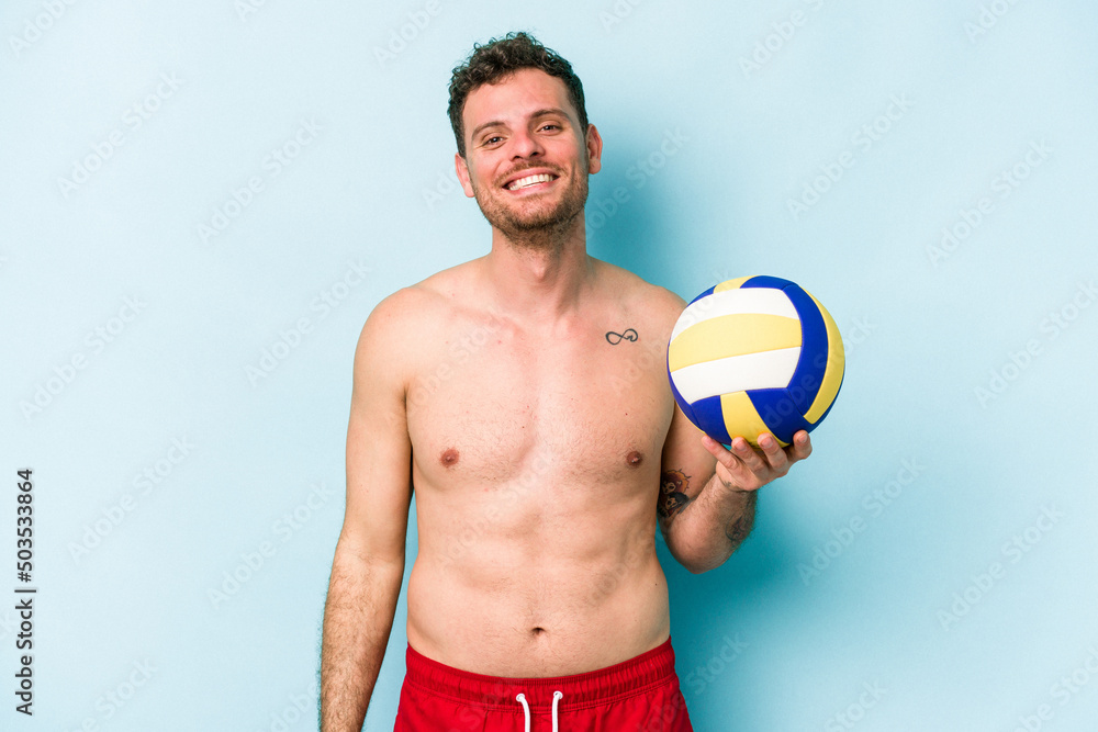 Young caucasian man playing volley isolated on blue background happy, smiling and cheerful.