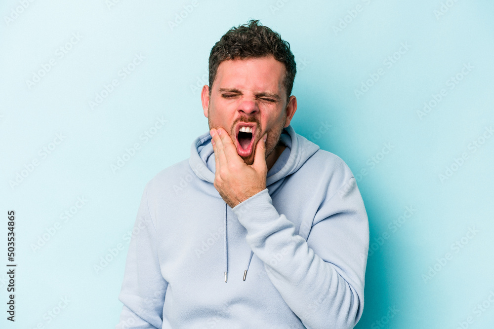 Young caucasian man isolated on blue background having a strong teeth pain, molar ache. Young caucasian man isolated on blue background having a strong teeth pain, molar ache.