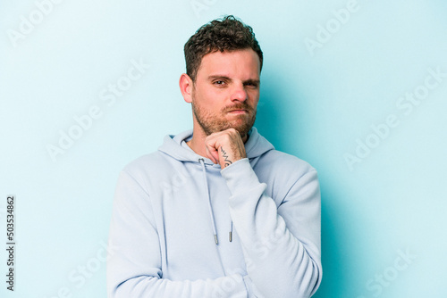 Young caucasian man isolated on blue background thinking and looking up, being reflective, contemplating, having a fantasy. © Asier