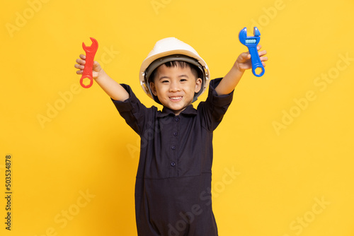 Asian little boy playing and showing repair tool isolated on yellow background, Technician kid concept