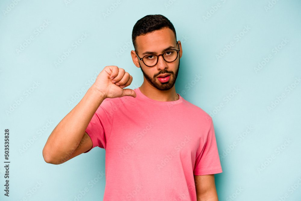 Young hispanic man isolated on blue background showing a dislike gesture, thumbs down. Disagreement concept. Young hispanic man isolated on blue background showing a dislike gesture, thumbs down. Disagreement concept.