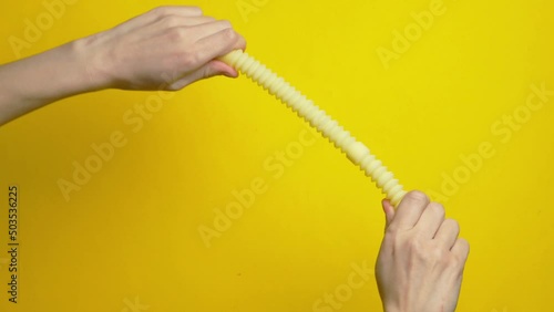 Female hands playing with antistress tube on yellow background