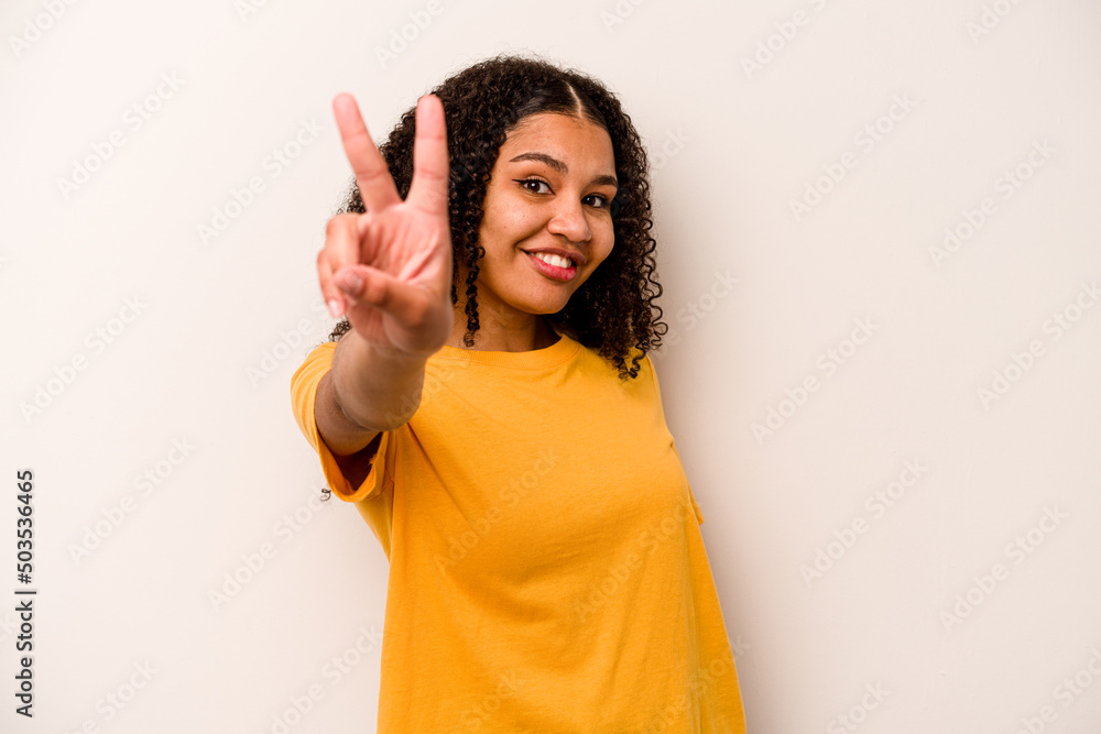 Young African American woman isolated on white background joyful and carefree showing a peace symbol with fingers. Young African American woman isolated on white background joyful and carefree showing a peace symbol with fingers.