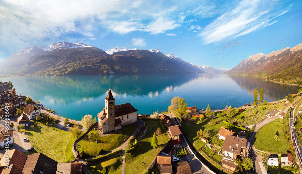 Stunning idylic nature scenery of lake Brienz with turquoise waters. Switzerland, Bern canton. Aerial view with little church in the morning light - obrazy, fototapety, plakaty 