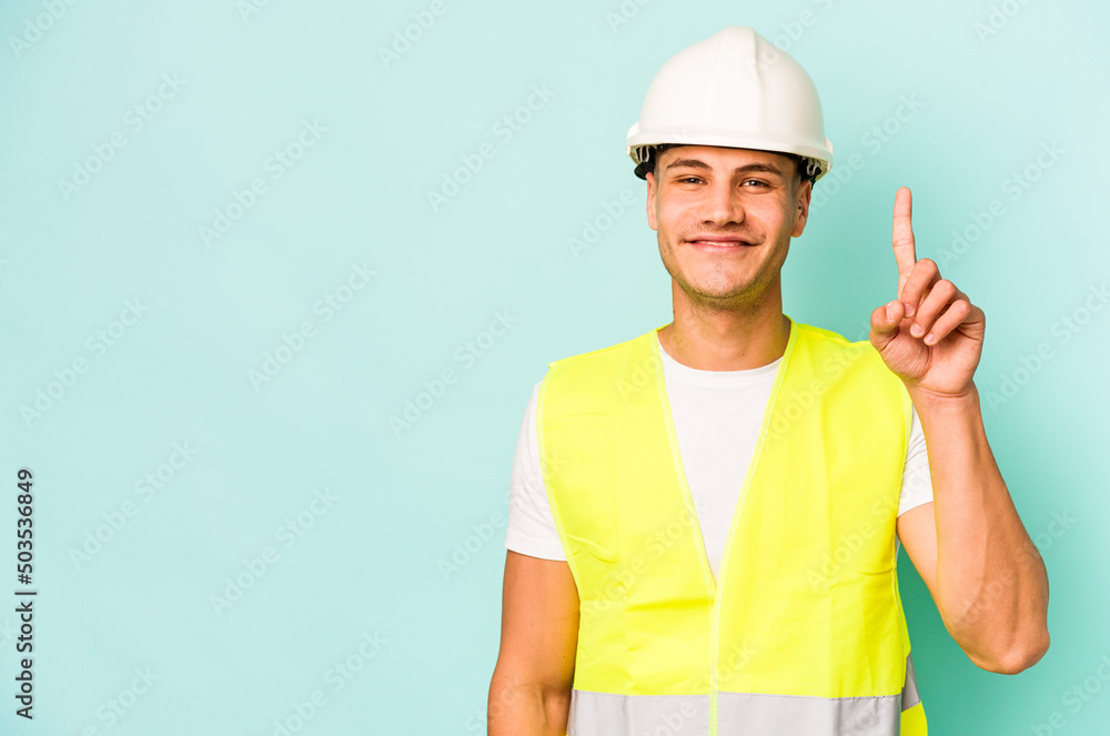 Young laborer caucasian man isolated on blue background showing number one with finger. Young laborer caucasian man isolated on blue background showing number one with finger.