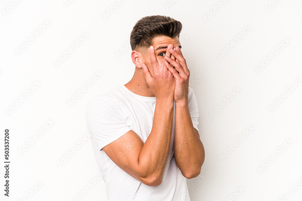 Young caucasian man isolated on white background blink through fingers frightened and nervous. Young caucasian man isolated on white background blink through fingers frightened and nervous.