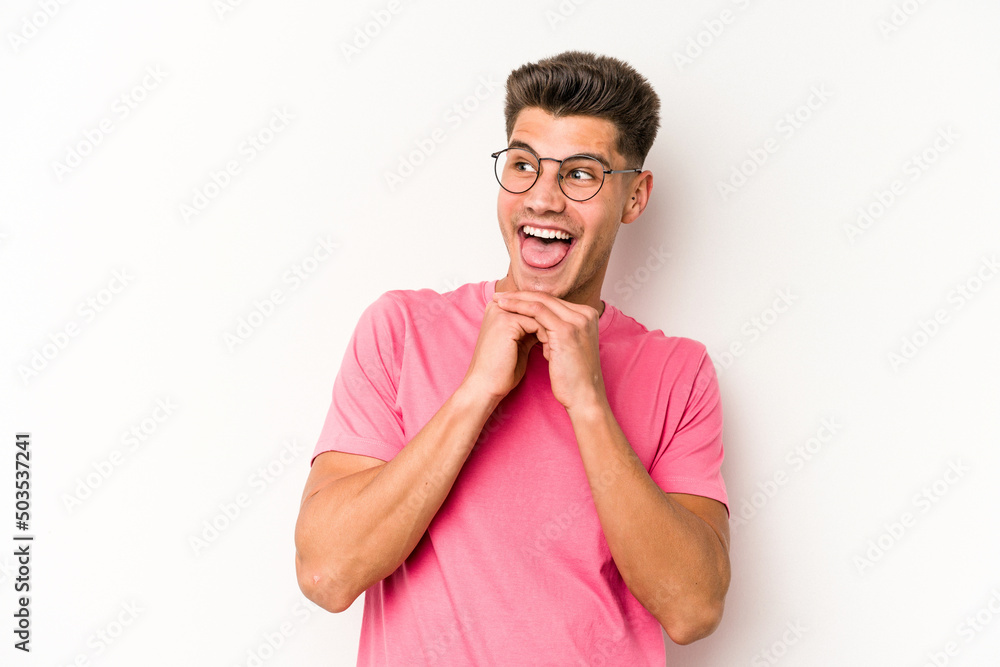 Young caucasian man isolated on white background keeps hands under chin, is looking happily aside. Young caucasian man isolated on white background keeps hands under chin, is looking happily aside.