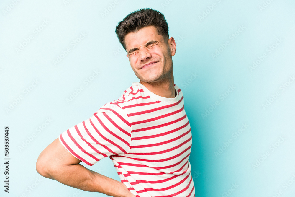 Young caucasian man isolated on blue background suffering a back pain. Young caucasian man isolated on blue background suffering a back pain.