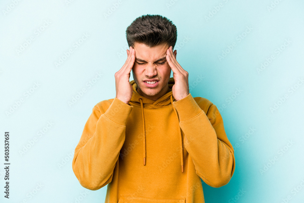 Young caucasian man isolated on blue background having a head ache, touching front of the face. Young caucasian man isolated on blue background having a head ache, touching front of the face.