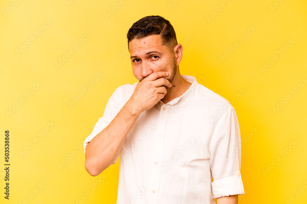 Young hispanic man isolated on yellow background covering mouth with hands looking worried. Young hispanic man isolated on yellow background covering mouth with hands looking worried.