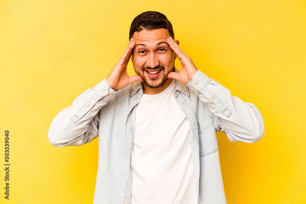 Young hispanic man isolated on yellow background receiving a pleasant surprise, excited and raising hands. Young hispanic man isolated on yellow background receiving a pleasant surprise, excited and raising hands.