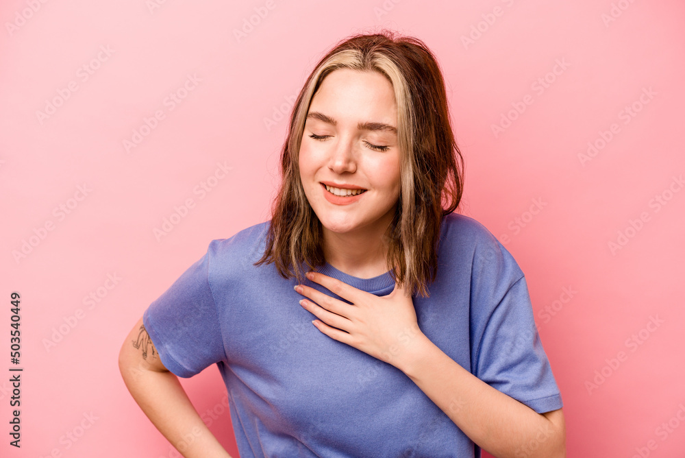Young caucasian woman isolated on pink background laughing keeping hands on heart, concept of happiness. Young caucasian woman isolated on pink background laughing keeping hands on heart, concept of happiness.