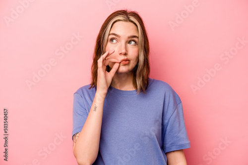 Young caucasian woman isolated on pink background with fingers on lips keeping a secret.