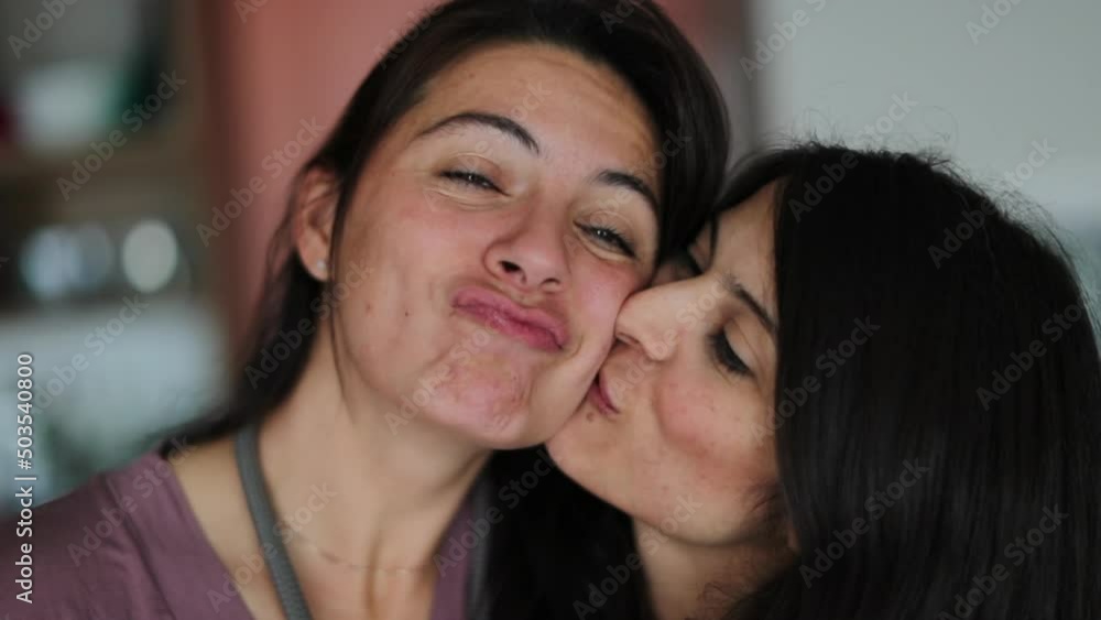 Family love sister kissing sibling on cheek smiling and laughing Family love sister kissing sibling on cheek smiling and laughing