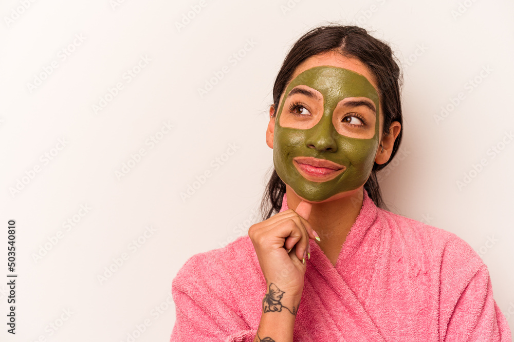 Young hispanic woman wearing a facial mask isolated on white background looking sideways with doubtful and skeptical expression. Young hispanic woman wearing a facial mask isolated on white background looking sideways with doubtful and skeptical expression.