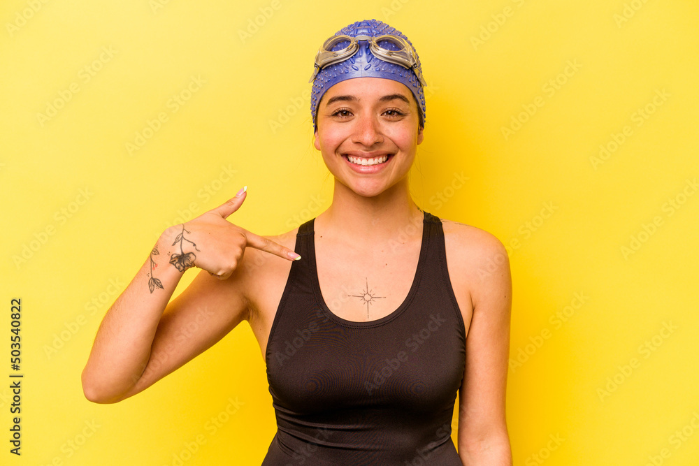 Young swimmer hispanic woman isolated on yellow background person pointing by hand to a shirt copy space, proud and confident Young swimmer hispanic woman isolated on yellow background person pointing by hand to a shirt copy space, proud and confident
