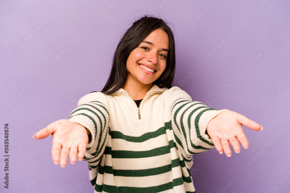 Young hispanic woman isolated on purple background showing a welcome expression. Young hispanic woman isolated on purple background showing a welcome expression.