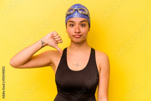 Young swimmer hispanic woman isolated on yellow background showing a dislike gesture, thumbs down. Disagreement concept.
