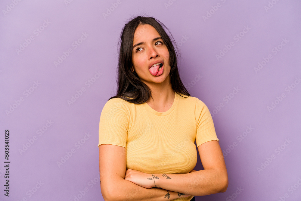 Young hispanic woman isolated on purple background funny and friendly sticking out tongue. Young hispanic woman isolated on purple background funny and friendly sticking out tongue.