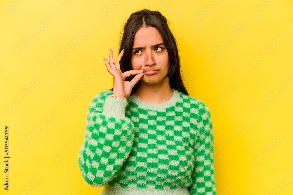 Young hispanic woman isolated on yellow background with fingers on lips keeping a secret. Young hispanic woman isolated on yellow background with fingers on lips keeping a secret.