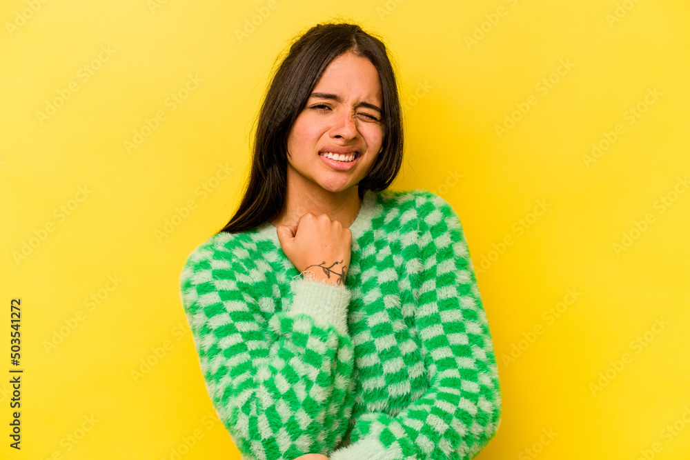 Young hispanic woman isolated on yellow background massaging elbow, suffering after a bad movement. Young hispanic woman isolated on yellow background massaging elbow, suffering after a bad movement.