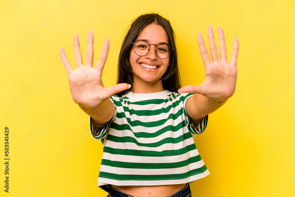 Young hispanic woman isolated on yellow background showing number ten with hands. Young hispanic woman isolated on yellow background showing number ten with hands.