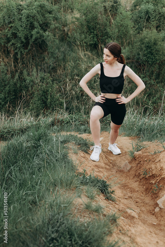 Portrait of fit and sporty young woman doing stretching on nature.