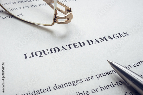 Documents about Liquidated damages with pen and glasses.