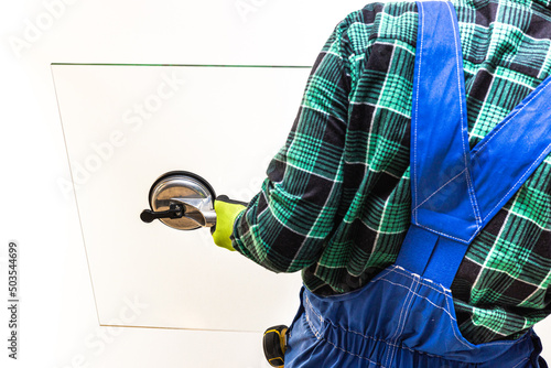 A glazier, worker holding a pane of thick glass in his hands with a special sucker photo