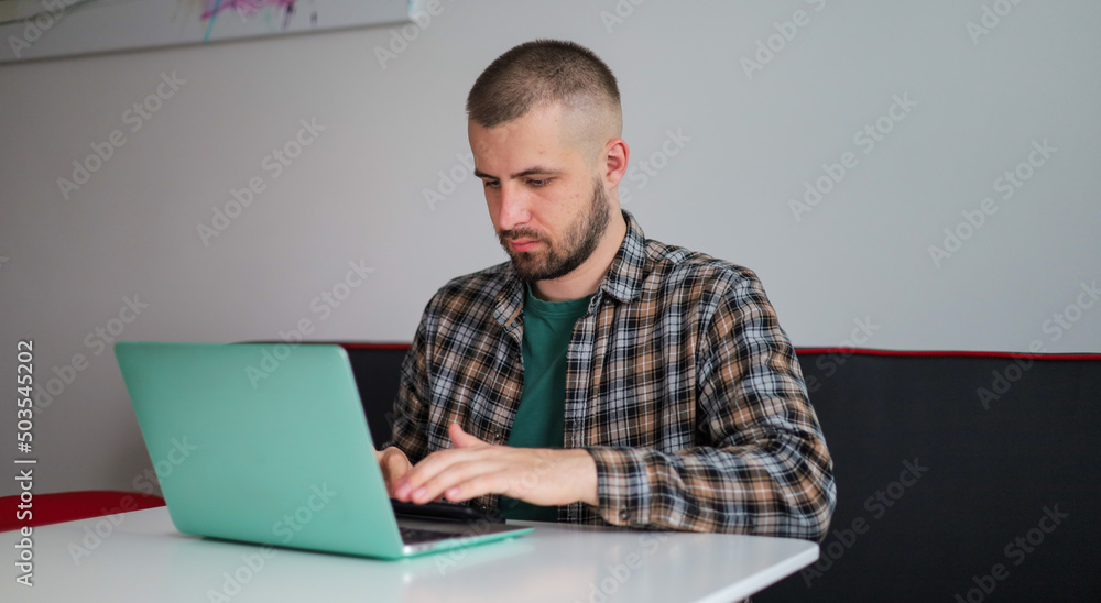 The guy in the shirt is working on the computer, working remotely. Freelancer. The guy in the shirt is working on the computer, working remotely. Freelancer.