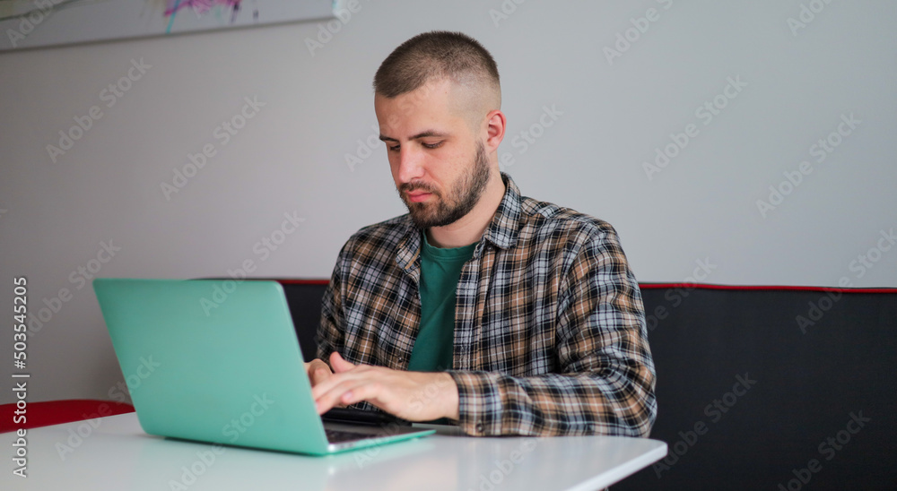 The guy in the shirt is working on the computer, working remotely. Freelancer. The guy in the shirt is working on the computer, working remotely. Freelancer.