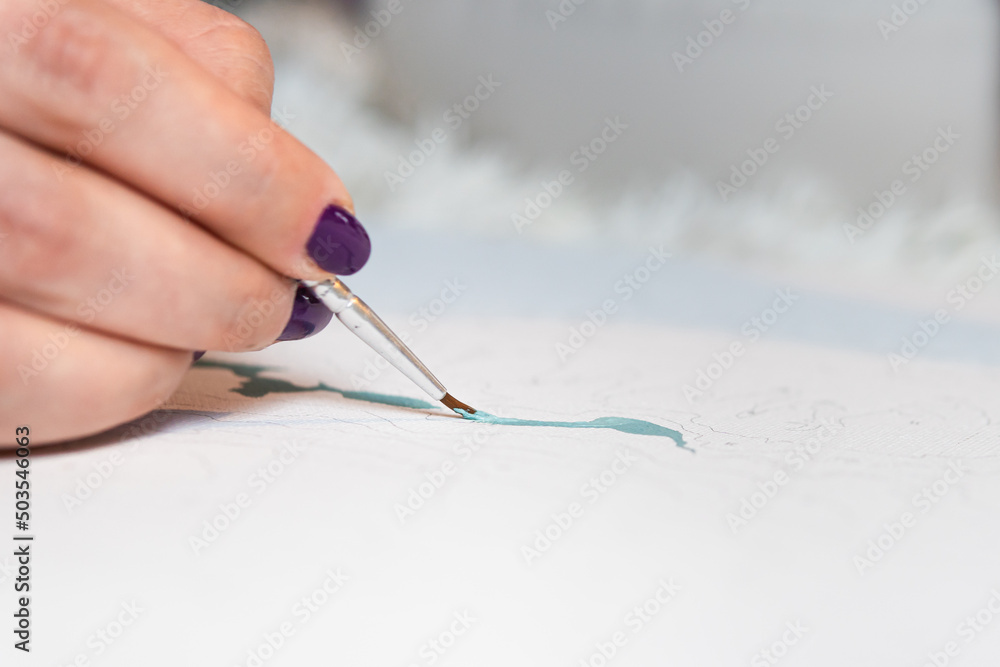 The adult woman painting by numbers indoors The adult woman painting by numbers indoors