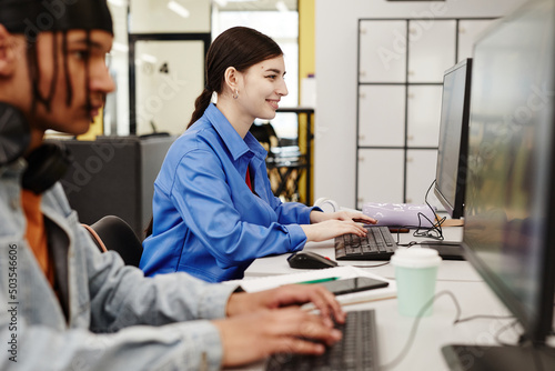 Wallpaper Mural Vibrant side view portrait of smiling young woman using computer in college library while doing research Torontodigital.ca