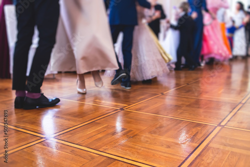 Couples dance on the historical costumed ball in historical dresses, classical ballroom dancers dancing, waltz, quadrille and polonaise in palace interiors on a wooden floor, charity event © tsuguliev