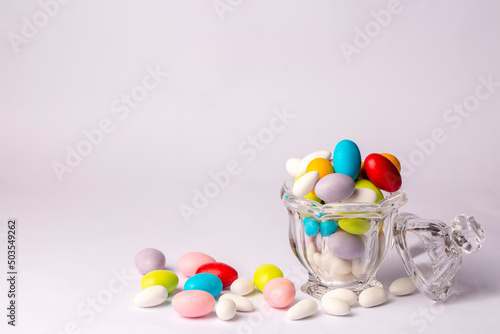 Colorful almond candies in the stylish,crystal candy bowl on white with copy space.The Sugar Feast concept. (Turkish name; Ramadan - Ramazan bayrami, Seker bayrami)