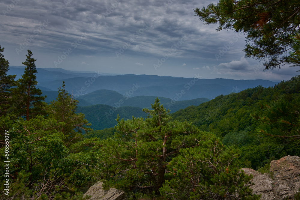 View over the mountains seen from a rocky mountainside with an overcast sky