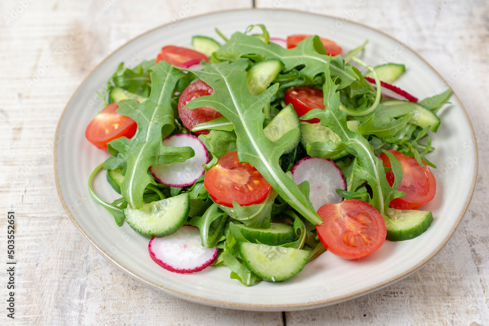 Spring vegan salad with spinach, cherry tomatoes, corn salad, baby spinach, cucumber and radish. Healthy food concept. Wooden table. Top view. Spring vegan salad with spinach, cherry tomatoes, corn salad, baby spinach, cucumber and radish. Healthy food concept. Wooden table. Top view.