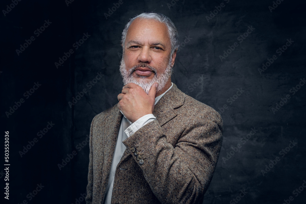 Studio shot of old fashioned elderly man dressed in beige tuxedo against dark background. Studio shot of old fashioned elderly man dressed in beige tuxedo against dark background.