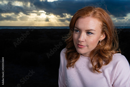 Pretty woman with red hair and freckles at the ocean beach